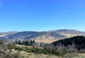 Panoramablick auf Hügel und Wälder vom Chalet 'Ronds Chetys' unter klarem Himmel in Frankreich.