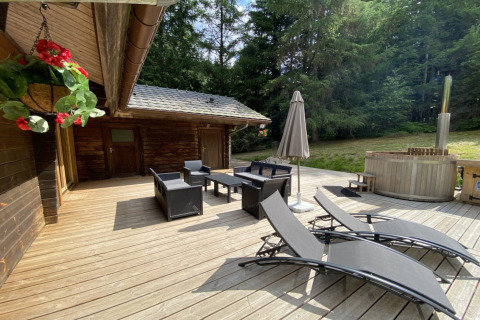 Houten terras aan LE FISHING LODGE in Frankrijk met ligzetels, zithoek, parasol en noordisch bad.