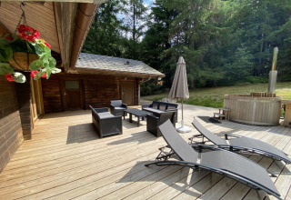 Houten terras bij LE FISHING LODGE in Frankrijk met ligstoelen, zithoek, parasol en een noordisch bad.