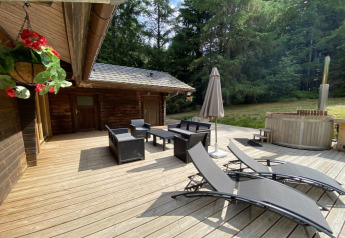 Houten terras bij LE FISHING LODGE in Frankrijk met ligstoelen, zithoek, parasol en een noordisch bad.