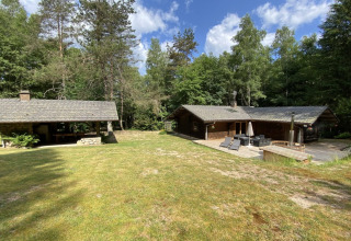 LE FISHING LODGE wooden chalet in France, surrounded by trees, patio and Nordic bath in a lush yard.