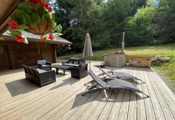 Buitenterras bij LE FISHING LODGE houten chalet in Frankrijk met loungehoek en Noordisch bad.