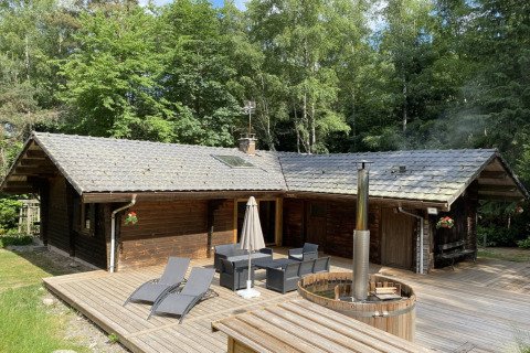 Houten chalet met Nordic bad en terras tussen bomen bij LE FISHING LODGE in Frankrijk.