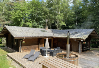 Houten chalet met Nordic bad en terras tussen bomen bij LE FISHING LODGE in Frankrijk.