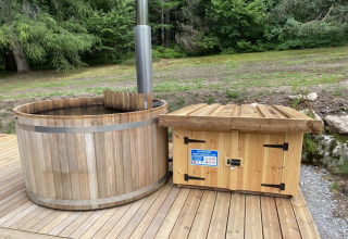 Houten Scandinavisch bad en schuurtje op terras bij LE FISHING LODGE chalet in Frankrijk, omgeven door groen.