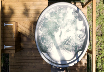 Bovenaanzicht van een bubbelbad op een houten terras bij Chartwell Luxury Dome, VK, omringd door natuur.