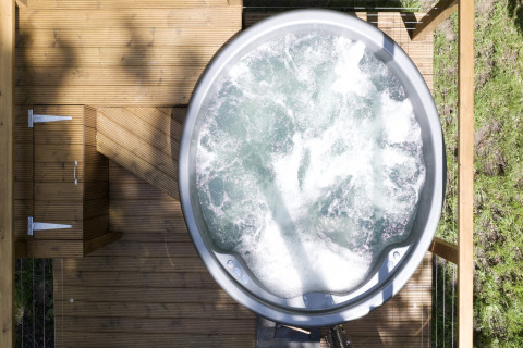 Bovenaanzicht van een bruisend bubbelbad op een houten terras bij Chartwell Luxury Dome, VK, omgeven door groen.