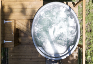 Top-down view of a bubbling hot tub on a wooden deck at Chartwell Luxury Dome, UK, surrounded by greenery.