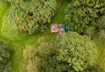Luchtfoto van Chartwell Luxury Dome in het VK, omringd door weelderige groene bomen en grasvelden.