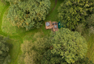 Aerial view of Chartwell Luxury Dome in the UK, nestled among lush green trees and grassy landscape.