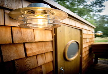 Buitenlamp op de houten gevel van Chartwell Luxury Dome in het Verenigd Koninkrijk naast een ronde deur.