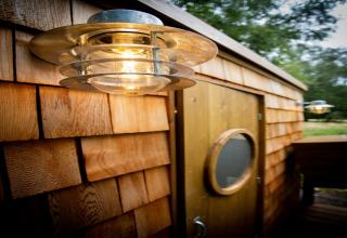Buitenverlichting aan de houten gevel van Chartwell Luxury Dome in het Verenigd Koninkrijk, naast een ronde deur.