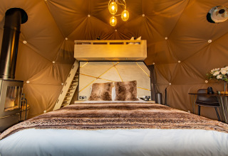 Elegant interior of Chartwell Luxury Dome featuring a cozy bed, wood stove, and lofted space in the United Kingdom.