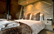 Moderne slaapkamer in Hever Luxury Dome, VK, met harig beddengoed en stijlvolle wandverlichting.