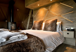 Moderne soveværelse i Hever Luxury Dome, Storbritannien, med plysset sengetæppe og dekorativ væg.