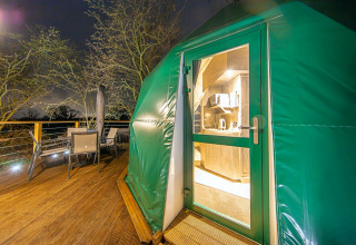 Udsigt til terrasse og indgang til Hever Luxury Dome i Storbritannien, oplyst om natten.