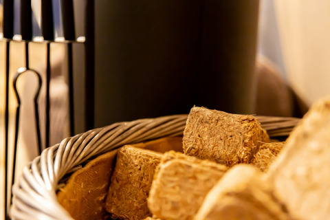 Basket of straw briquettes in front of a fireplace inside a dome, creating a warm and cozy setting.