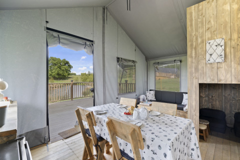 Interieur van The Herdwick Safari Tent in het VK, met eethoek, terras en uitzicht op bomen en water.