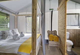 Interieur van de Herdwick Safari Tent met hemelbed, handdoeken en natuurrijk uitzicht in het Verenigd Koninkrijk.