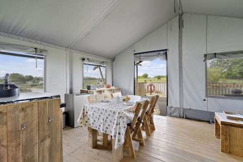 Binnenkant van de Herdwick Safari Tent in het VK, met houten meubels en uitzicht op het platteland.