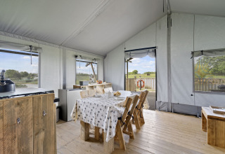Binnenkant van de Herdwick Safari Tent in het VK, met houten meubels en uitzicht op het platteland.