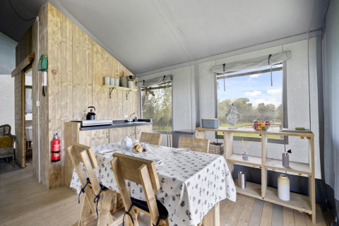 Interieur van de Herdwick Safari Tent in het Verenigd Koninkrijk met eettafel, keuken en uitzicht op natuur.