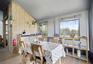 Interieur van de Herdwick Safari Tent in het Verenigd Koninkrijk met eettafel, keuken en uitzicht op natuur.