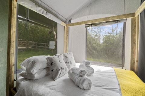 Slaapkamer in The Herdwick Safari Tent met comfortabel beddengoed, handdoeken en uitzicht op de natuur.