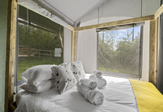 Slaapkamer in The Herdwick Safari Tent met comfortabel beddengoed, handdoeken en uitzicht op de natuur.