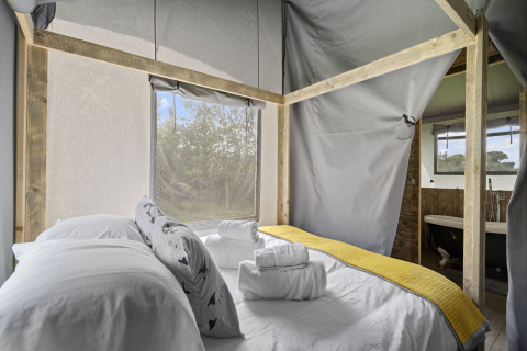 Interieur van de Herdwick Safari Tent in het Verenigd Koninkrijk, met een tweepersoonsbed en geel kleed.