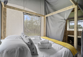Interieur van de Herdwick Safari Tent in het Verenigd Koninkrijk, met een tweepersoonsbed en geel kleed.