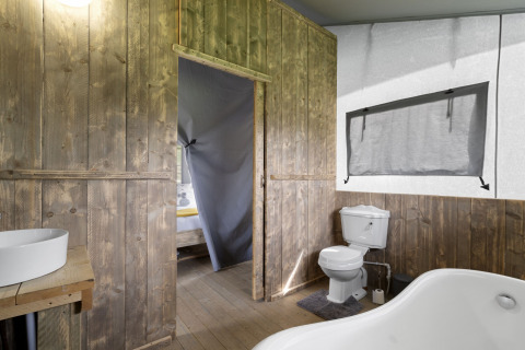 Badkamer met houten panelen, wastafel, toilet en bad in The Herdwick Safari Tent, Verenigd Koninkrijk.
