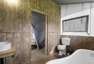 Badkamer met houten panelen, wastafel, toilet en bad in The Herdwick Safari Tent, Verenigd Koninkrijk.