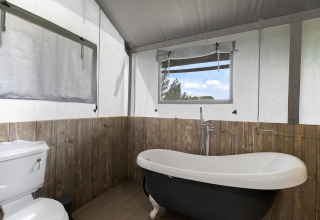 Badkamer in de Herdwick Safari Tent in het Verenigd Koninkrijk met vrijstaand bad en toilet.