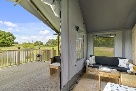 De Herdwick Safari Tent in het Verenigd Koninkrijk met houten terras en knusse zithoek bij het meer.