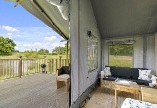 De Herdwick Safari Tent in het Verenigd Koninkrijk met houten terras en knusse zithoek bij het meer.
