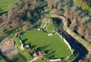 Luchtfoto van The Herdwick Safari Tent in het Verenigd Koninkrijk, met grasvelden en kasteelruïnes tussen bomen.