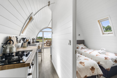 Interieur van de Highland Camping Pod in het Verenigd Koninkrijk met keuken en slaapkamer met twee bedden.