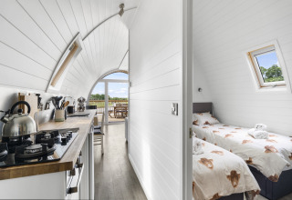 Interieur van de Highland Camping Pod in het Verenigd Koninkrijk met keuken en slaapkamer met twee bedden.