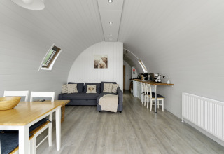 Modern ingericht interieur van The Highland Camping Pod in het VK met bank, eettafel en keukenhoek.
