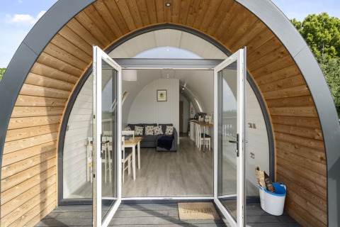 Ingang van The Highland Camping Pod in het Verenigd Koninkrijk met open deuren en modern interieur.