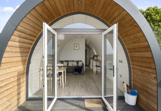 Ingang van The Highland Camping Pod in het Verenigd Koninkrijk met open deuren en modern interieur.