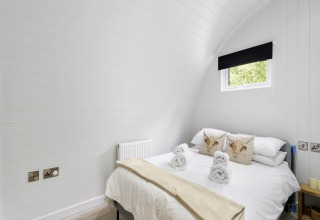 Lichte slaapkamer in The Highland Camping Pod, Verenigd Koninkrijk, met tweepersoonsbed en klein raam.