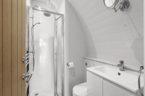 Modern badkamer in The Highland Camping Pod, VK, met douche, wastafel en compact toilet.