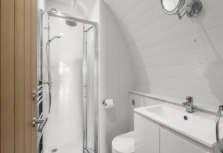 Modern badkamer in The Highland Camping Pod, VK, met douche, wastafel en compact toilet.