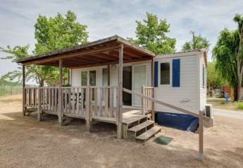 Casa móvil llamada Cottage Cesenatico con porche de madera cubierto y rampa, rodeada de naturaleza.