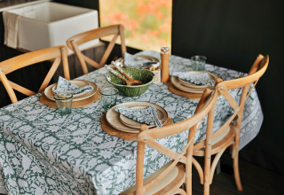 Gedekte eettafel in een safaritent met houten stoelen, patroon tafelkleed en stijlvol servies in het Verenigd Koninkrijk.