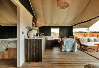 Interieur van een luxe safaritent met slaapkamer, keuken en eetgedeelte bij Owls Nest in het Verenigd Koninkrijk.