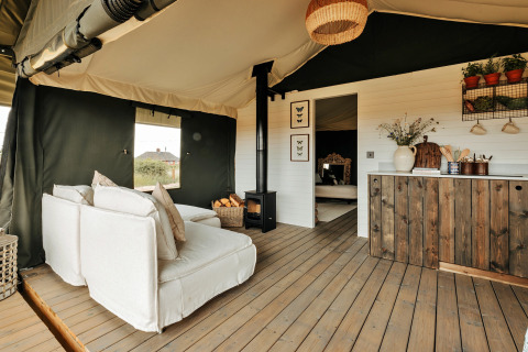 Knusse lounge in safaritent Owls Nest, Verenigd Koninkrijk, met houten vloer en sfeervolle landelijke inrichting.