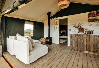 Knusse lounge in safaritent Owls Nest, Verenigd Koninkrijk, met houten vloer en sfeervolle landelijke inrichting.